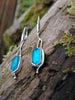 Sterling silver long drop earrings with sky blue agate rose cut oblong flowers. sitting on a mossy log in the sunshine