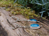 Sterling silver long drop earrings with sky blue agate rose cut oblong flowers. sitting on a mossy log in the sunshine