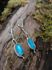 Sterling silver long drop earrings with sky blue agate rose cut oblong flowers. sitting on a mossy log in the sunshine