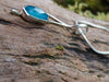 Sterling silver long drop pendant with sky blue agate rose cut oblong flower and silver snake chain. sitting on a mossy log in the sunshine